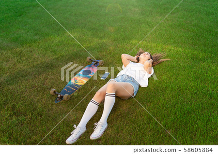 Young girl enjoy lay in green lawn and listening 58605884