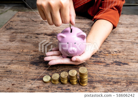 women hand putting gold coin into pink piggy bank with golden coins growth bar graph, step up growing business to success and saving for retirement concept women hand putting gold coin into pink piggy bank with golden coins growth bar graph, step up growing business to success and saving for retirement concept 58606242