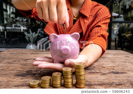 woman hand putting gold coin into pink piggy bank with golden coins growth bar graph, step up growing business to success and saving for retirement concept 58606243
