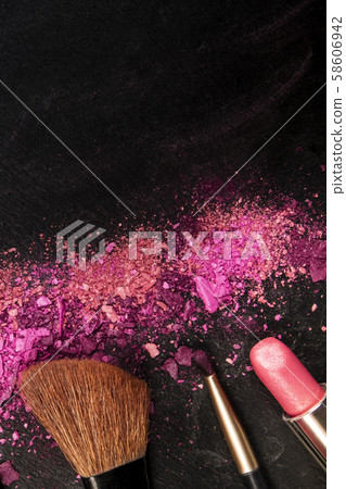 Make-up brushes, lipstick, and crushed cosmetics, overhead shot on a black background texture with a Make-up brushes, lipstick, and crushed cosmetics, overhead shot on a black background texture with a 58606942
