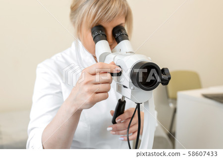 Female blond doctor gynecologist looks through a 58607433