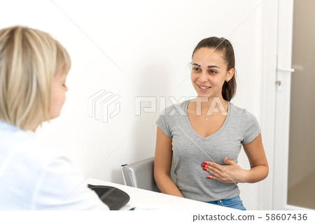 A young girl shows where she hurts, at a doctors A young girl shows where she hurts, at a doctors 58607436