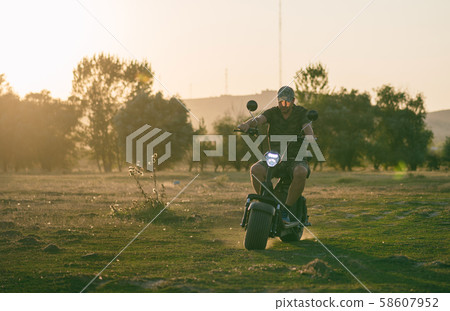 man on a motorized bicycle in sunset time 58607952