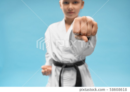 Confident junior in white kimono practicing punching. Confident junior in white kimono practicing punching. 58608618