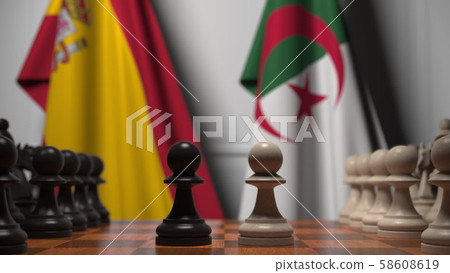Flags of Spain and Algeria behind pawns on the chessboard. Chess game or political rivalry related Flags of Spain and Algeria behind pawns on the chessboard. Chess game or political rivalry related 58608619