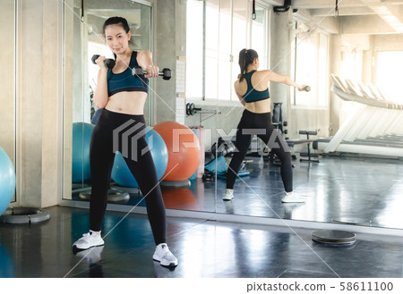 Sporty fit woman workout exercises with dumbbells. 58611100