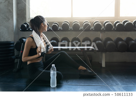 Fit young woman sitting on gym floor for relaxing Fit young woman sitting on gym floor for relaxing 58611133