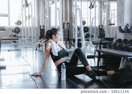 Fit young woman sitting on gym floor for relaxing 58611134