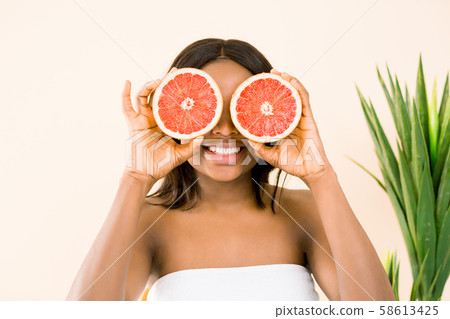 Beauty african woman with orange citrus grapefruit cover eyes with healthy skin body, isolated over 58613425