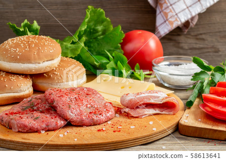 Process of cooking homemade burgers, meatballs, tomatoes, cheese and other ingredients on a wooden 58613641
