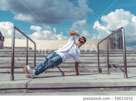 dancer on one arm dances break dance, hip-hop. In summer, city background steps clouds. Active youth dancer on one arm dances break dance, hip-hop. In summer, city background steps clouds. Active youth 58613858