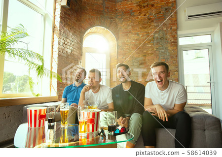 Group of friends watching football or soccer game on TV at home 58614039