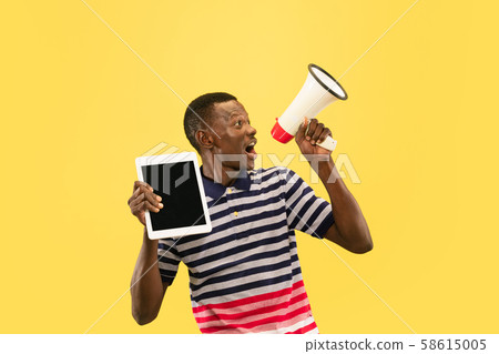 Young african-american man isolated on yellow studio background, human emotions concept. 58615005