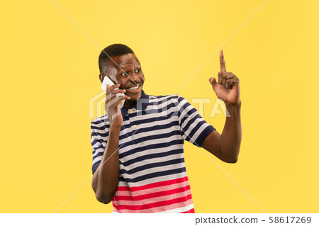 Young african-american man isolated on yellow studio background, human emotions concept. Young african-american man isolated on yellow studio background, human emotions concept. 58617269