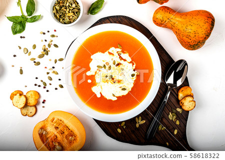 Pumpkin cream soup with milk on the white background. Close-up. 58618322