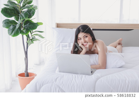 Charming woman smiles and lies on the bed with 58618832