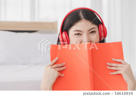 Beautiful woman wearing red headphones listening 58618939