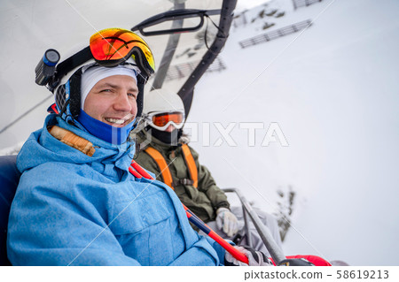 Image of two snowboarders in helmet and mask on cable car . 58619213