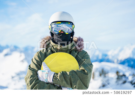 Portrait of man in helmet with snowboard standing on snow resort . Portrait of man in helmet with snowboard standing on snow resort . 58619297