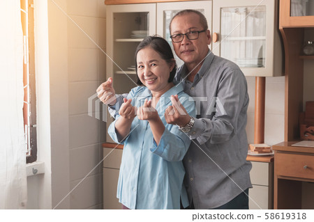 Elderly husband and wife raise hands to show love 58619318
