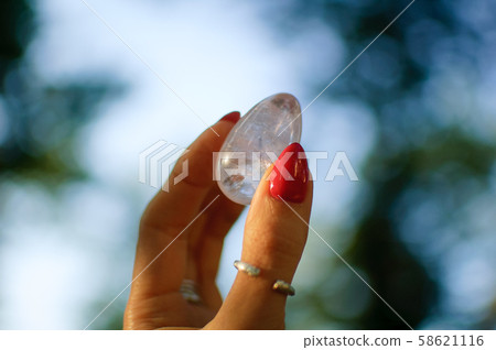Female hand with transparent amethyst quartz yoni egg for vumfit, imbuilding or meditation. Shining Female hand with transparent amethyst quartz yoni egg for vumfit, imbuilding or meditation. Shining 58621116