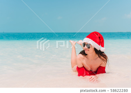 Young woman in Santa Hat walking spread her hands on white sandy beach 58622280