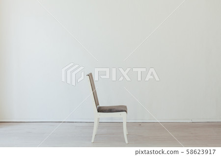 one gray chair in the interior of an empty white room 58623917