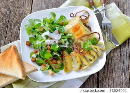 Fried Swabian meat ravioli (so called 'Maultaschen') served with corn salad with croutons and bacon Fried Swabian meat ravioli (so called 'Maultaschen') served with corn salad with croutons and bacon 58624961