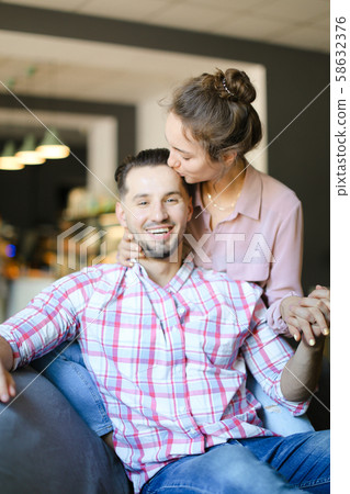 Young lovely wife kissing husband at home. Young lovely wife kissing husband at home. 58632376