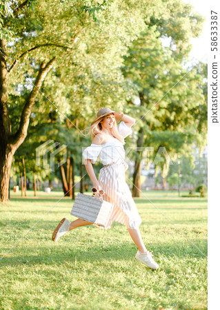 Young pretty girl jumping in park and running, wearing fashionable clothes and hat. Young pretty girl jumping in park and running, wearing fashionable clothes and hat. 58633387