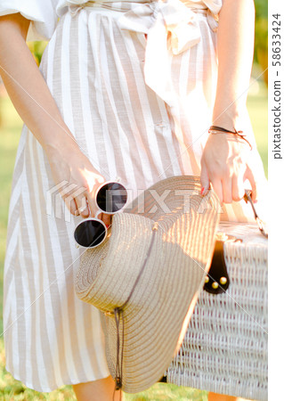 Close up bag, hat and black sunglasses in female hands. 58633424
