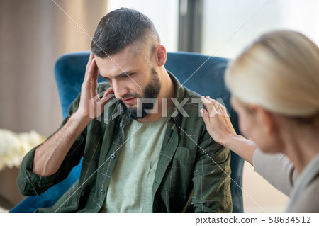 Man having headache while sharing concerns with psychoanalyst Man having headache while sharing concerns with psychoanalyst 58634512