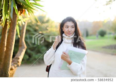Japanese girl with documents walking in park. 58634952