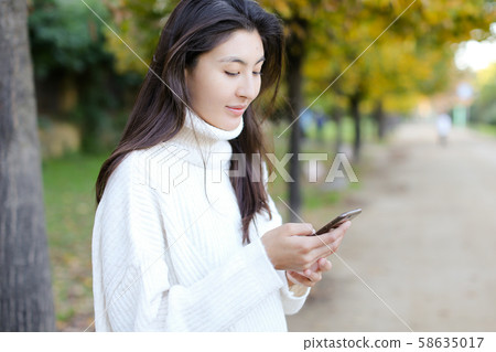 Korean girl using smartphone and walking in park. 58635017