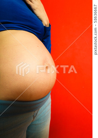 Adult woman showing her pregnant belly Adult woman showing her pregnant belly 58636667