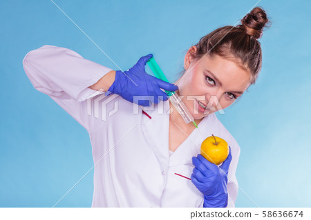 Scientist doctor injecting apple. GM Food. 58636674