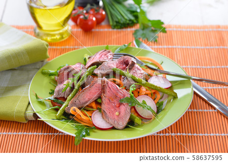 Mixed spring salad with roasted asparagus and medium fried beef steak cut into strips 58637595