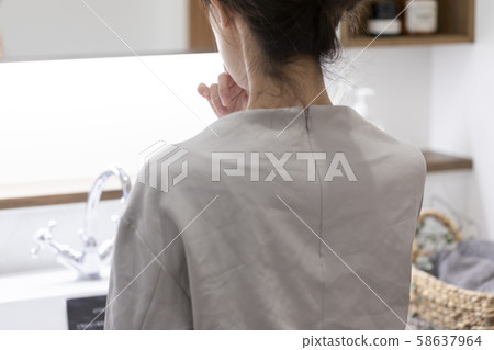 Back view of young woman doing makeup at vanity in bathroom 58637964