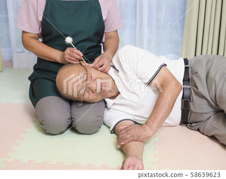 Senior couple cleaning their ears with knee pillows 58639623