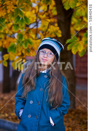 A teenager girl in glasses, a coat and a knitted 58640438