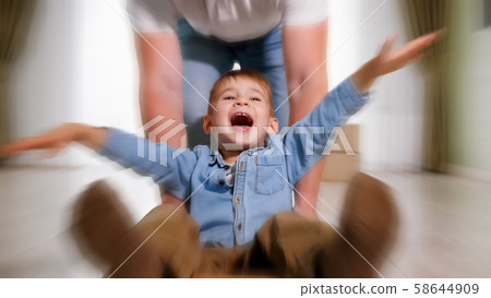 father wearing white shirt rides smiling son in craft box 58644909