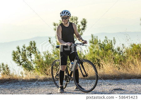 Male cyclist standing with his bike Male cyclist standing with his bike 58645423