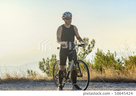 Male cyclist standing with his bike Male cyclist standing with his bike 58645424