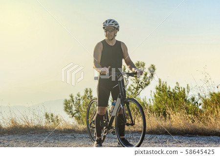 Male cyclist standing with his bike Male cyclist standing with his bike 58645425