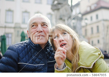 Outdoors portrait of elderly man and his young blonde wife spending time together in the ancient Outdoors portrait of elderly man and his young blonde wife spending time together in the ancient 58647935