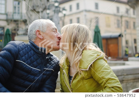 Portrait of happy romantic couple with age difference kissing outdoors in the ancient city during Portrait of happy romantic couple with age difference kissing outdoors in the ancient city during 58647952