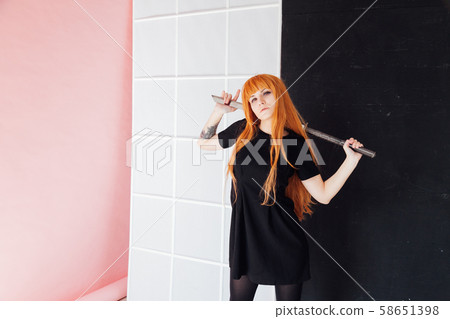 Woman cosplayer with red hair holds Japanese sword 58651398