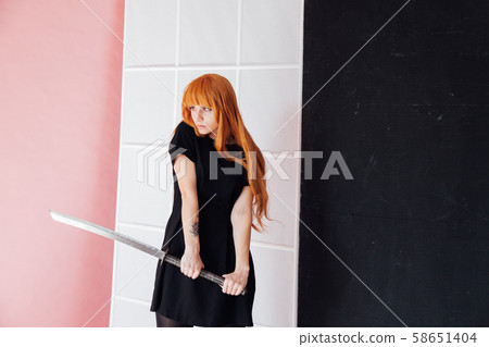 Woman cosplayer with red hair holds Japanese sword Woman cosplayer with red hair holds Japanese sword 58651404