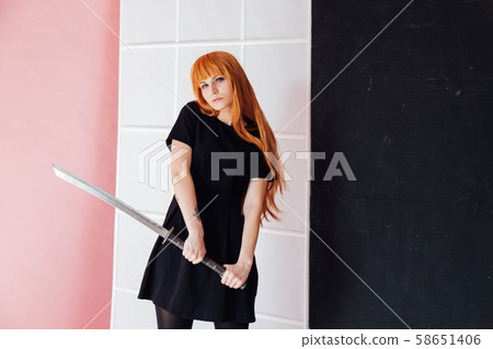 Woman cosplayer with red hair holds Japanese sword Woman cosplayer with red hair holds Japanese sword 58651406