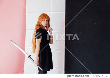 Woman cosplayer with red hair holds Japanese sword Woman cosplayer with red hair holds Japanese sword 58651407